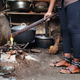 A survivor of breast ironing holds a stick used for breast ironing over a fire for a demonstration in Douala, Cameroon,